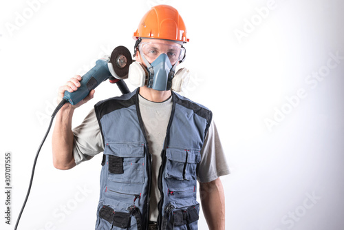 A builder in a helmet and a respirator, with an angle grinder on his shoulder.