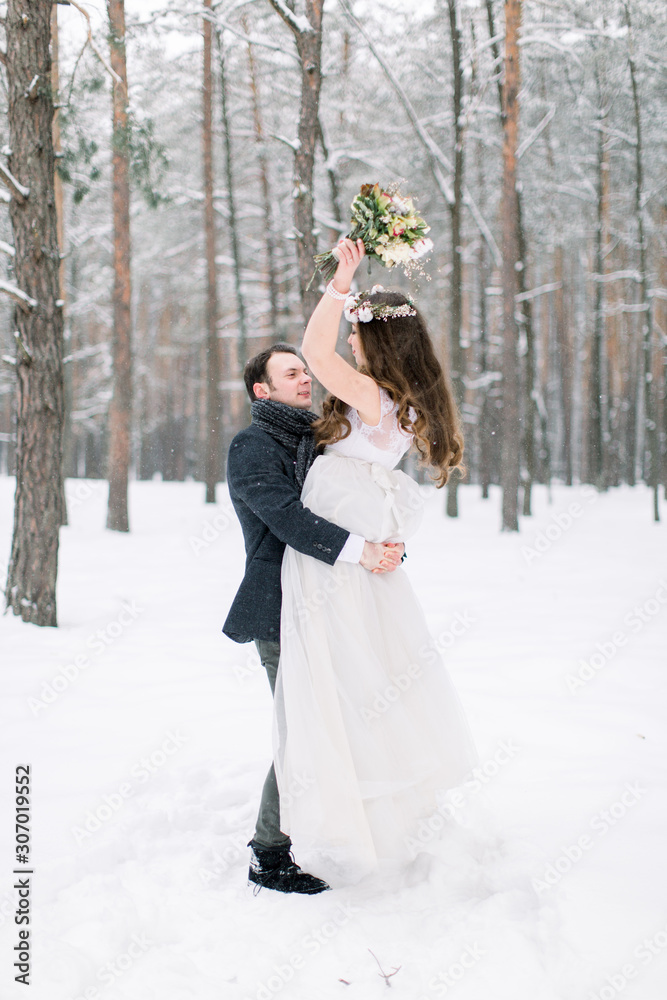 Wedding in winter forest. Boy and girl in the winter forest. Hug love couple, man holds woman on hands Wedding in winter forest. Boy and girl in the winter forest. Hug love couple, man holds woman on hands