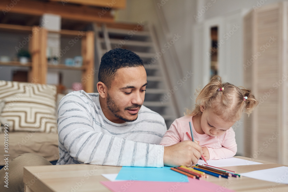 Portrait of contemporary mixed-race man drawing together with cute daughter at home, copy space Portrait of contemporary mixed-race man drawing together with cute daughter at home, copy space