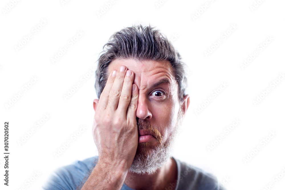 A portrait of bearded man with closed one eye with his hand. People and emotions concept A portrait of bearded man with closed one eye with his hand. People and emotions concept