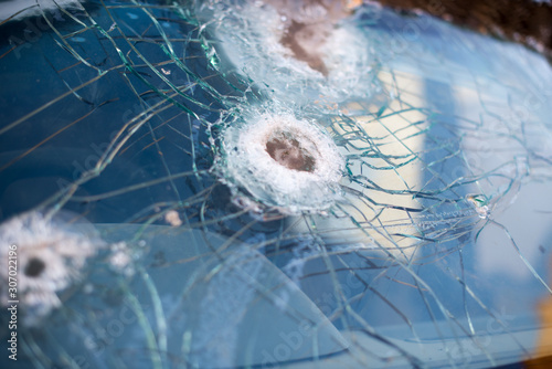 Bullet hole on a car windshield. Car window after a raid has a bullet hole. Broken glass. Bullet holes in a front windshield. Broken Windshield. © Alex