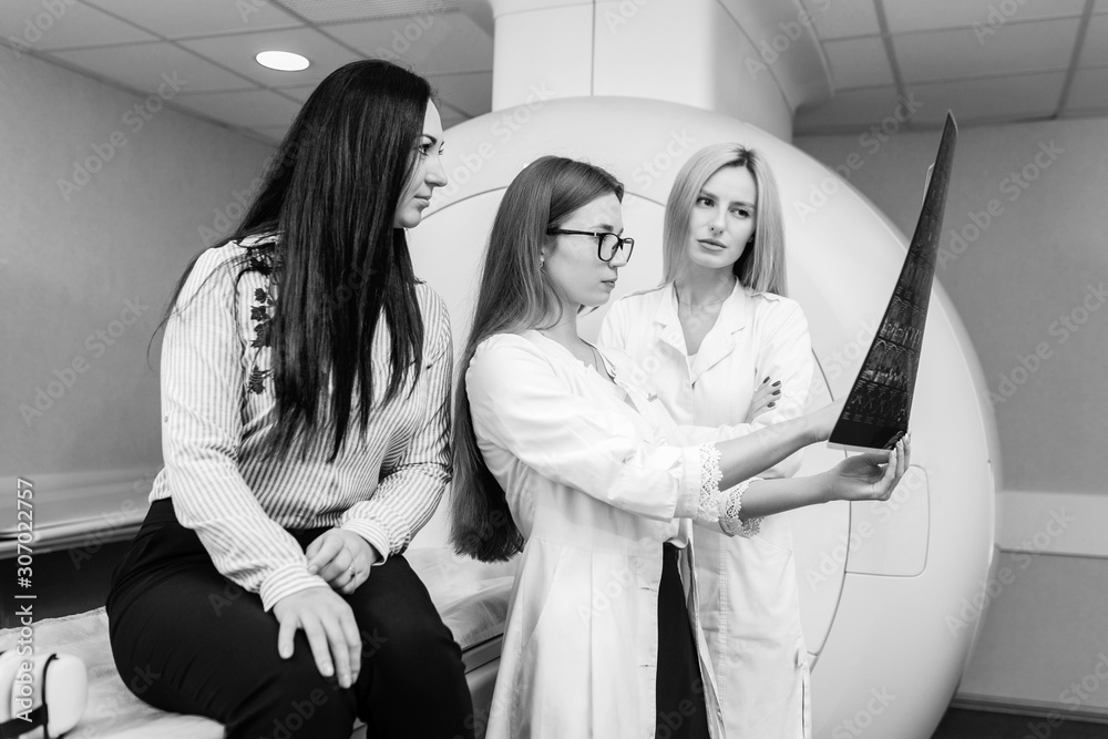 Two female models doctors examining patient and hold a picture in their