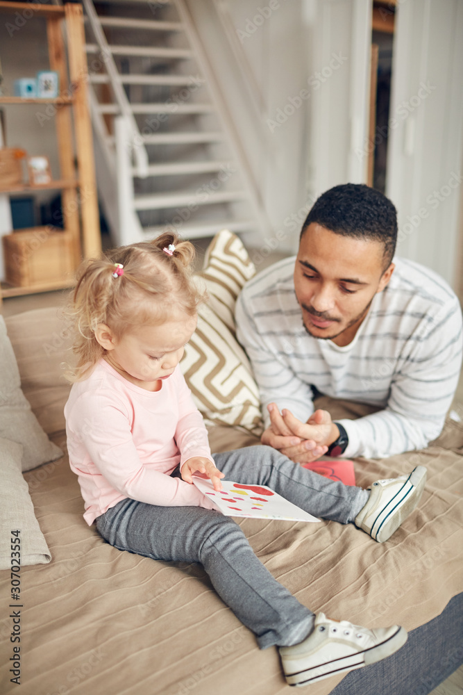 High angle portrait of cute little girl showing I love you card to dad while enjoying time together in home interior High angle portrait of cute little girl showing I love you card to dad while enjoying time together in home interior