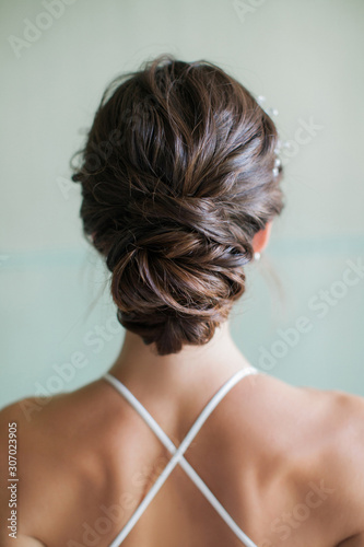 A young bride shows off her elegant dress and hairstyle from the back.