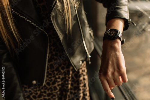 Black watch with golden arrows on a woman's hand. Fashion watches in a modern style