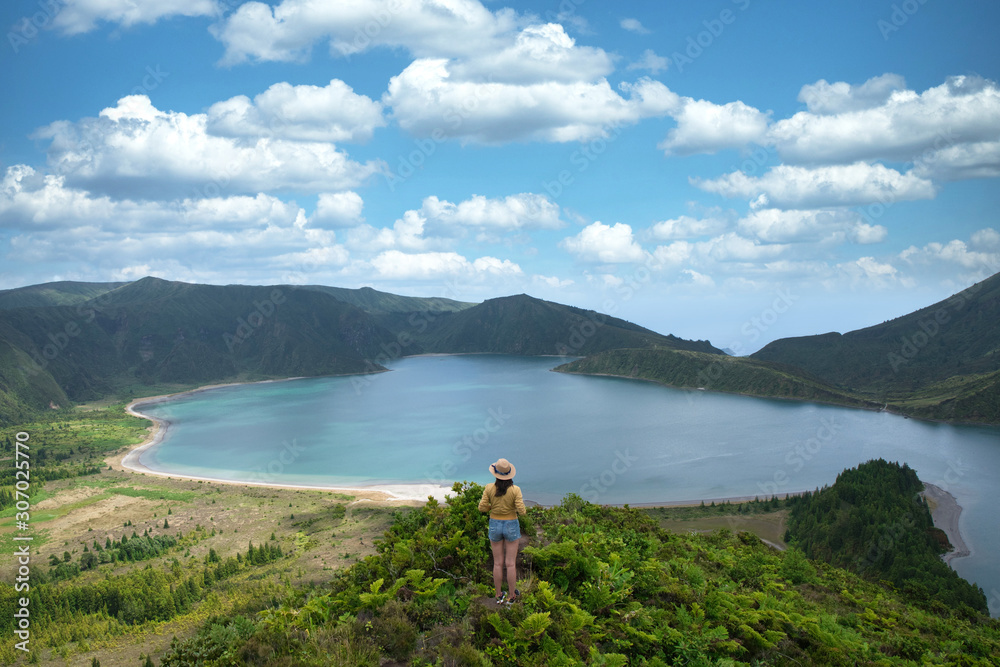 woman traveler holding hat and looking at amazing mountains and forest, wanderlust travel concept, space for text, atmospheric epic moment, azores ,portuhal, ponta delgada, sao miguel