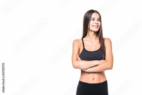 Happy fitness woman standing with arms folded over white background and looking at camera