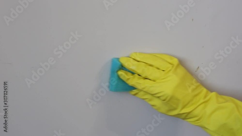 Female hand in yellow gloves cleaning wall with a sponge. Cleaning supplies and disinfect concept. Footage.