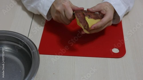 Woman hands peeling of poteto.