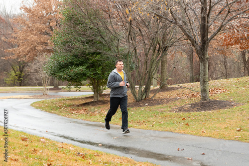 middle aged handsome man running on path in rain