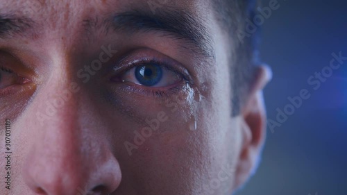 Close-up eye of depressed man crying with tears. Concept of despair.