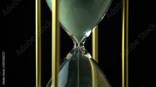 Hourglass clock time concept. Old vintage gold metal frame green sand clock countdown on dark background. Close up.