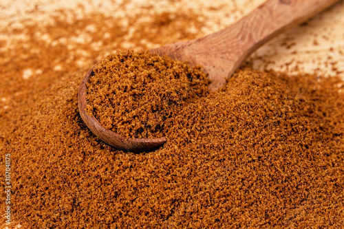 Spoon full of dark brown sugar  on a wooden background