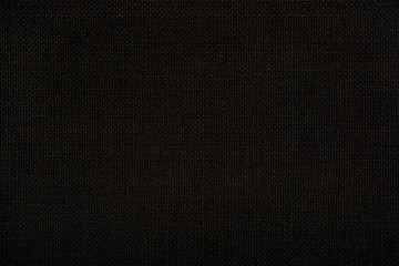 Close up texture of natural weave hessian woven cloth in dark black color. Fabric texture of natural bagging jute or burlap or linen textile material. Seamless background.