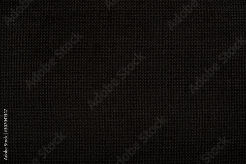 Close up texture of natural weave hessian woven cloth in dark black color. Fabric texture of natural bagging jute or burlap or linen textile material. Seamless background.