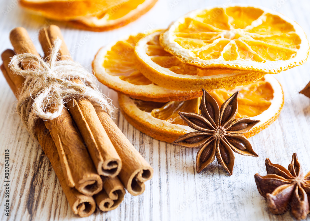Christmas spices - cinnamon sticks, star anise, and slices of dried orange on old wooden background.
