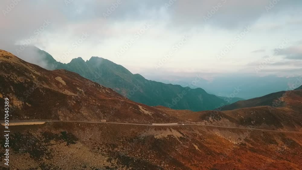 Aerial: Panoramic of mountain pass road in the Alps in Europe during golden morning sun
