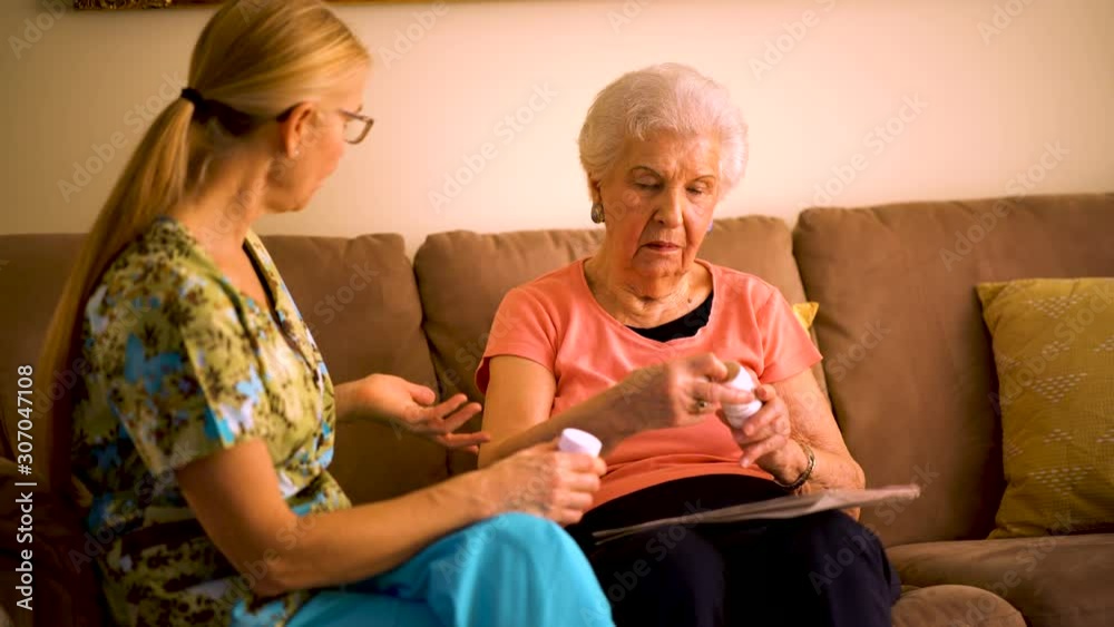 Closeup of home healthcare nurse going over medications with elderly woman while sitting in living room.