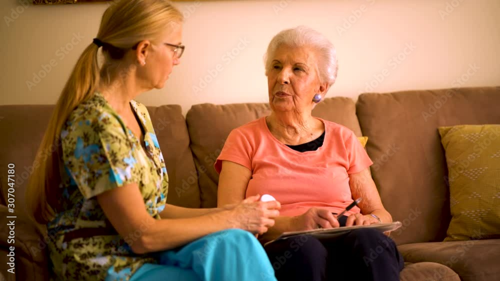 Closeup of home healthcare nurse going over medications with elderly woman while sitting in living room. Closeup of home healthcare nurse going over medications with elderly woman while sitting in living room.