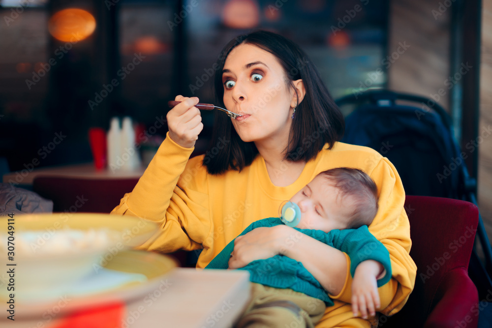 Obraz premium Mom Eating Holding Sleeping Baby at the Table