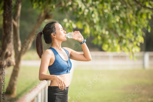 beautiful young woman drinking water after training