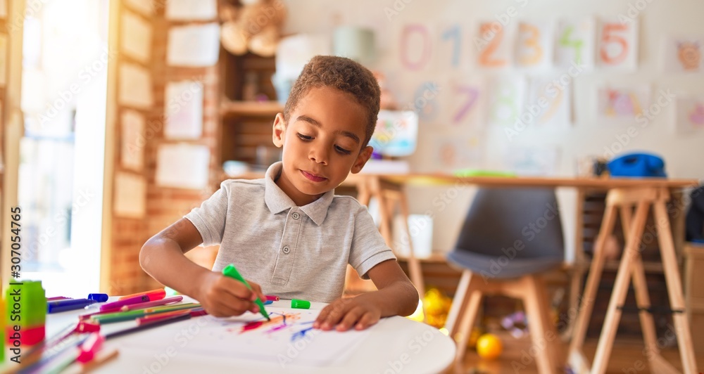 Naklejka premium Beautiful african american toddler drawing using paper and marker pen at kindergarten