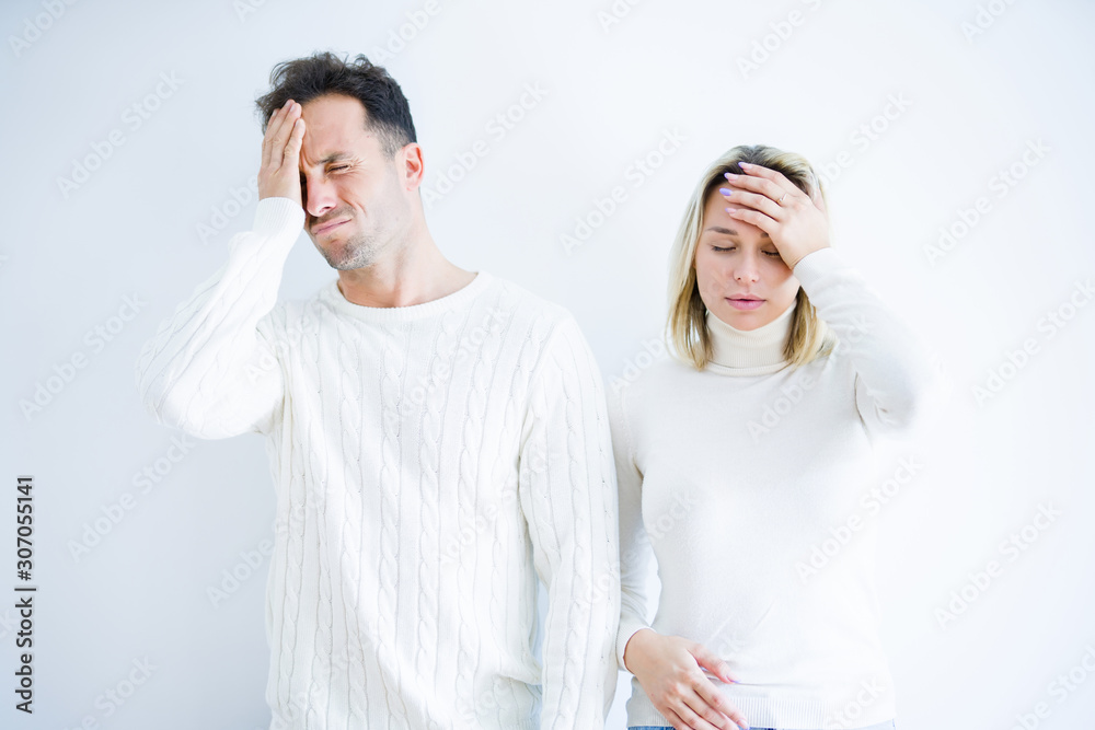 Young beautiful couple wearing casual t-shirt standing over isolated white background suffering from headache desperate and stressed because pain and migraine. Hands on head. Young beautiful couple wearing casual t-shirt standing over isolated white background suffering from headache desperate and stressed because pain and migraine. Hands on head.