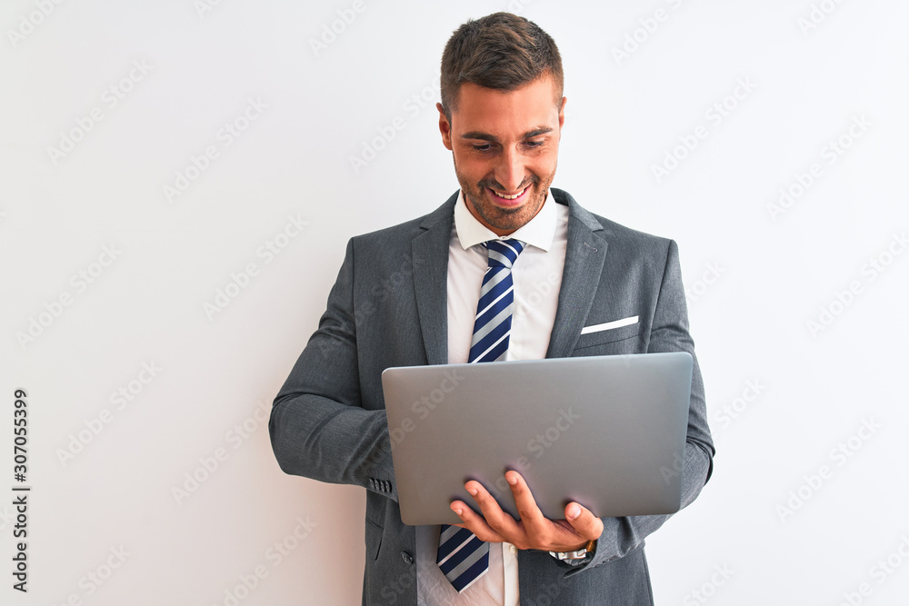 Young handsome business man working using computer laptop over isolated background with a happy face standing and smiling with a confident smile showing teeth Young handsome business man working using computer laptop over isolated background with a happy face standing and smiling with a confident smile showing teeth