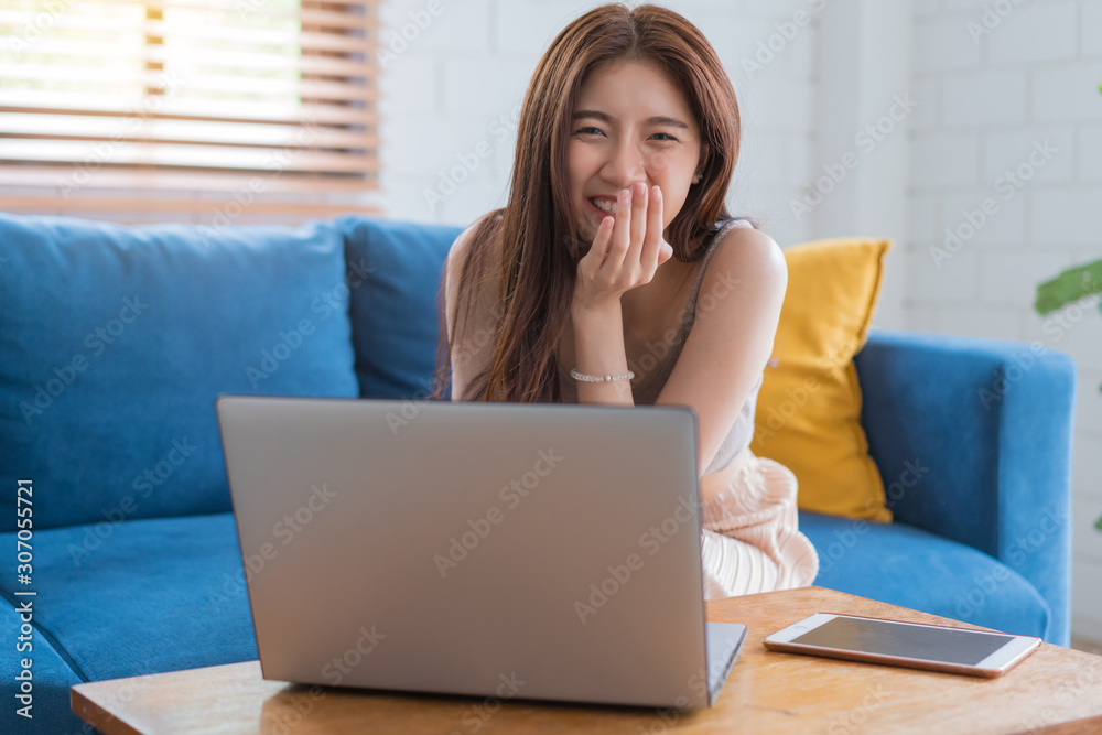 Asian woman relaxing sitting on sofa using computer notbeook at living room, Education technology and internet concept. Asian woman relaxing sitting on sofa using computer notbeook at living room, Education technology and internet concept.