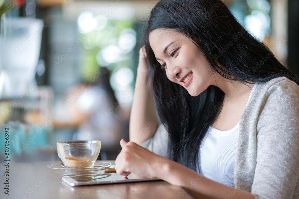 Beautiful woman in a coffee cafe uses a smartphone with relaxing Beautiful woman in a coffee cafe uses a smartphone with relaxing