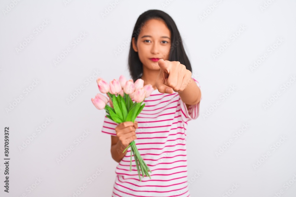 Young chinese woman holding bouquet of roses standing over isolated white background pointing with finger to the camera and to you, hand sign, positive and confident gesture from the front Young chinese woman holding bouquet of roses standing over isolated white background pointing with finger to the camera and to you, hand sign, positive and confident gesture from the front