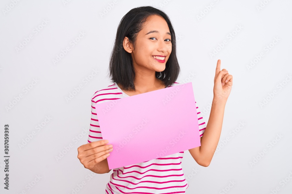 Young beautiful chinese woman holding banner standing over isolated white background very happy pointing with hand and finger to the side Young beautiful chinese woman holding banner standing over isolated white background very happy pointing with hand and finger to the side
