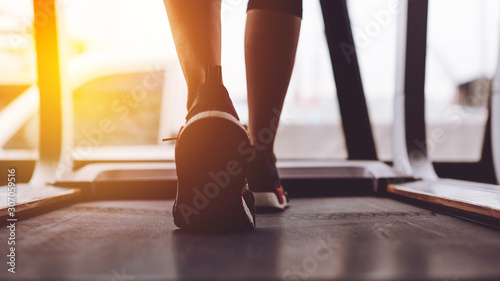Close up shoes woman's muscular legs feet running on treadmill workout at fitness gym.