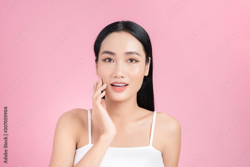 Beautiful young Asian girl touching her perfect skin on pink background. Skin care concept Beautiful young Asian girl touching her perfect skin on pink background. Skin care concept
