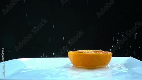 Oranges slowly falling into the water on black background photo