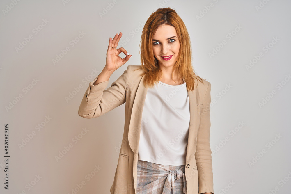 Redhead caucasian business woman standing over isolated background smiling positive doing ok sign with hand and fingers. Successful expression. Redhead caucasian business woman standing over isolated background smiling positive doing ok sign with hand and fingers. Successful expression.