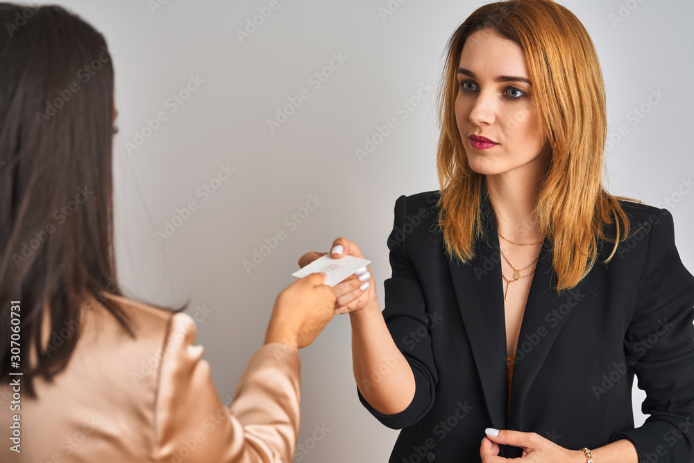 Two young beautiful businesswomen exchanging visit card Two young beautiful businesswomen exchanging visit card