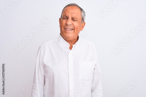 Senior grey-haired man wearing elegant shirt standing over isolated white background winking looking at the camera with sexy expression, cheerful and happy face.