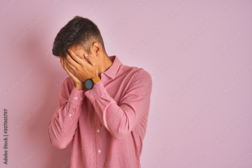 Young indian man wearing elegant shirt standing over isolated pink background with sad expression covering face with hands while crying. Depression concept. Young indian man wearing elegant shirt standing over isolated pink background with sad expression covering face with hands while crying. Depression concept.