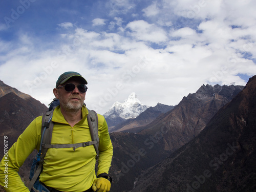 Male tourist with a backpack in the mountains. Himalayas, Nepal. In the background is AMA Dablam, one of the most beautiful peaks in the Everest region.