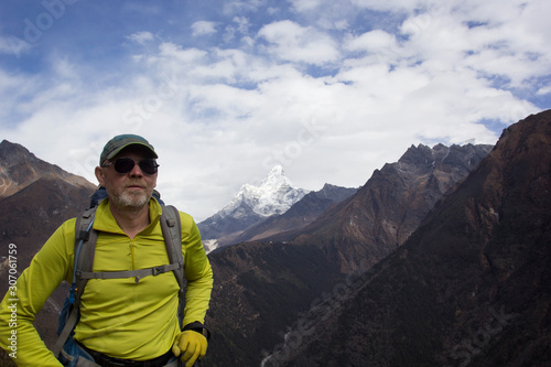 Male tourist with a backpack in the mountains. Himalayas, Nepal. In the background is AMA Dablam, one of the most beautiful peaks in the Everest region.