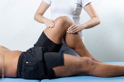 Therapist treating injured knee of athlete male patient - sport physical therapy concept.