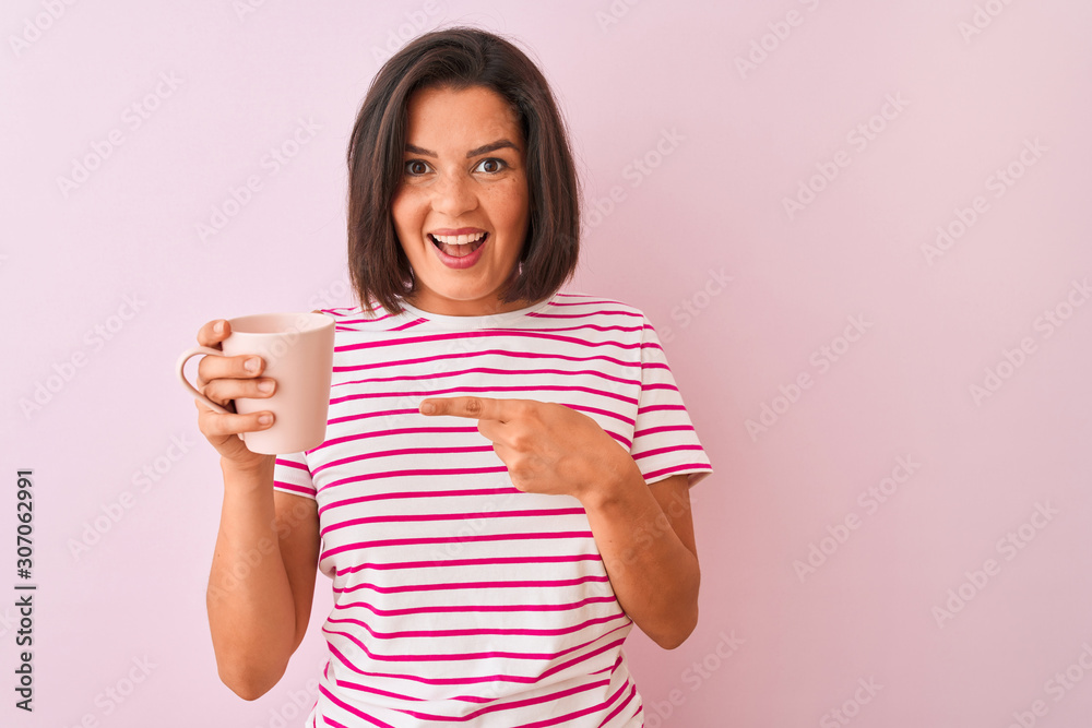 Young beautiful woman drinking cup of coffee standing over isolated pink background very happy pointing with hand and finger Young beautiful woman drinking cup of coffee standing over isolated pink background very happy pointing with hand and finger