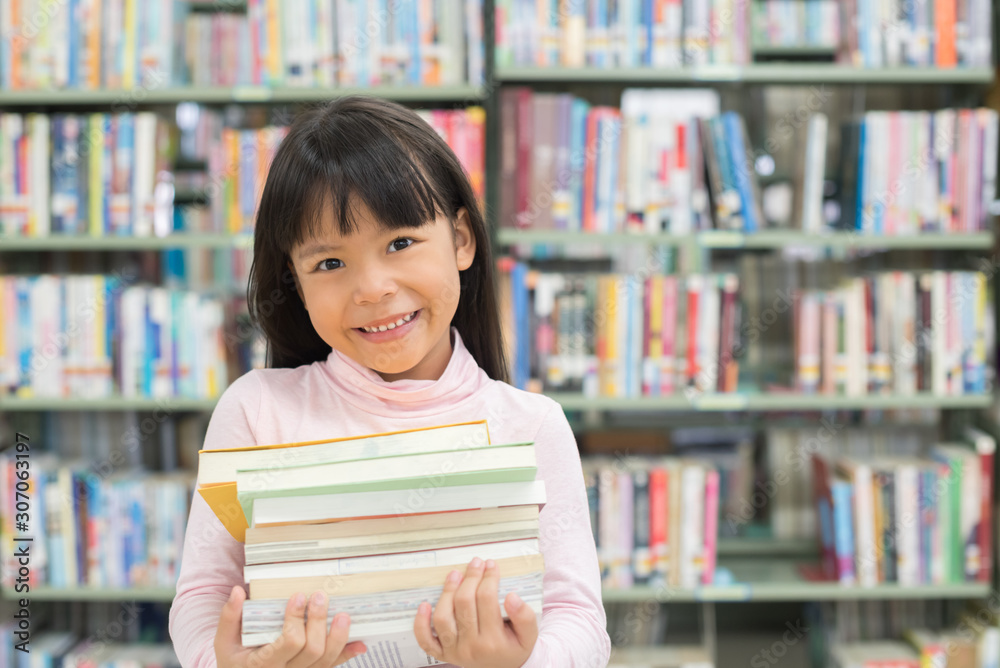 child girl holding a stack of books in the library child girl holding a stack of books in the library