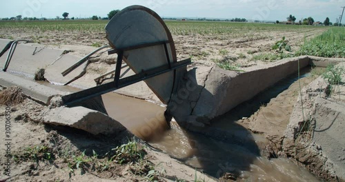 Cement irrigation ditch with head gate open to control flow  photo