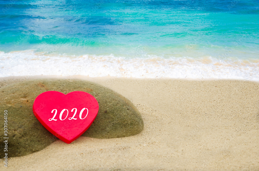 Fototapeta premium Symbol from number 2020 on the big heart on the sandy beach