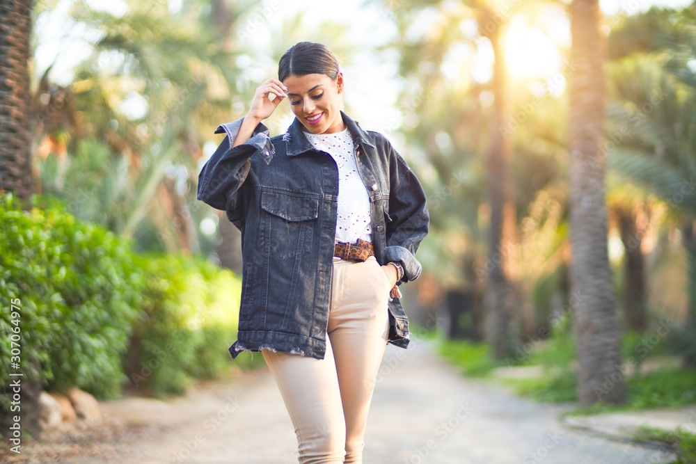 Young beautiful woman wearing denim jacket smiling happy and confident. Standing with smile on face at the town park Young beautiful woman wearing denim jacket smiling happy and confident. Standing with smile on face at the town park