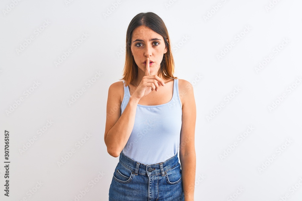 Beautiful redhead woman standing over isolated background asking to be quiet with finger on lips. Silence and secret concept. Beautiful redhead woman standing over isolated background asking to be quiet with finger on lips. Silence and secret concept.