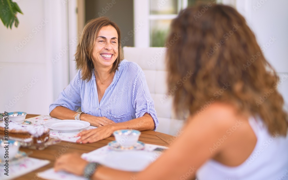 Fototapeta premium Young beautiful girl smiling happy and confident sitting dinking cup of coffee at terrace