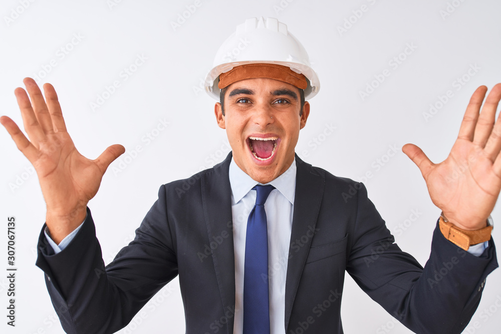 Young handsome architect man wearing suit and helmet over isolated white background celebrating crazy and amazed for success with arms raised and open eyes screaming excited. Winner concept Young handsome architect man wearing suit and helmet over isolated white background celebrating crazy and amazed for success with arms raised and open eyes screaming excited. Winner concept